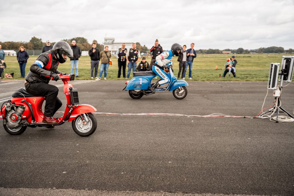 Glaube Vespa fährt gegen rote Vespa